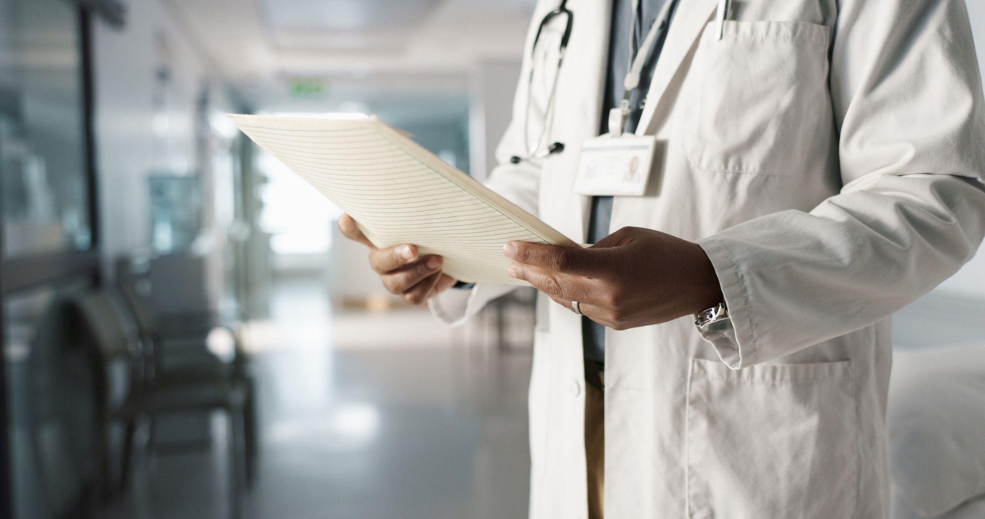 Un médico sostiene un trozo de papel en el pasillo de un hospital.
