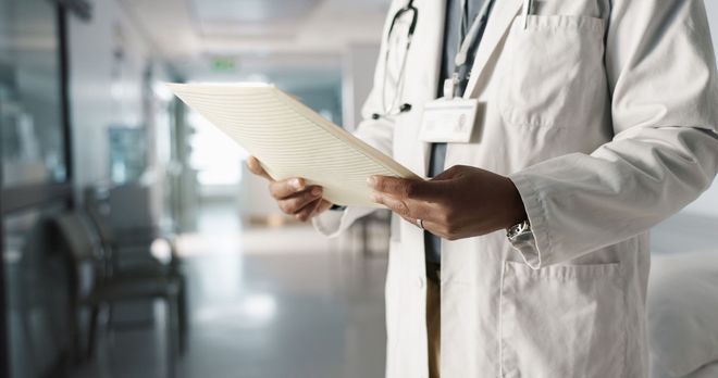 Un médico sostiene un trozo de papel en el pasillo de un hospital.