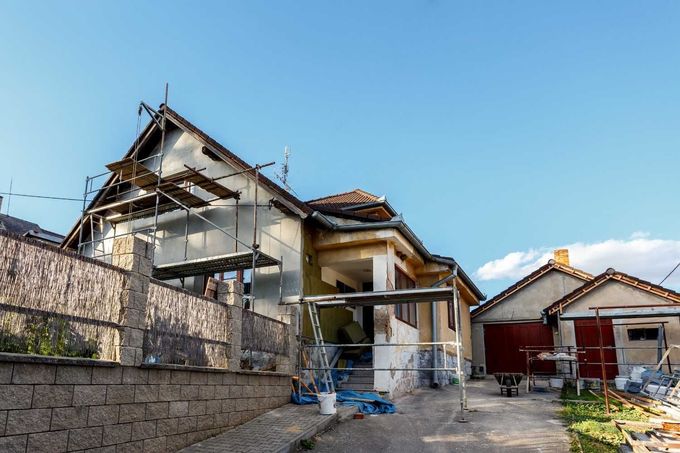 Exterior de casa en construcción, andamios, cielo azul.