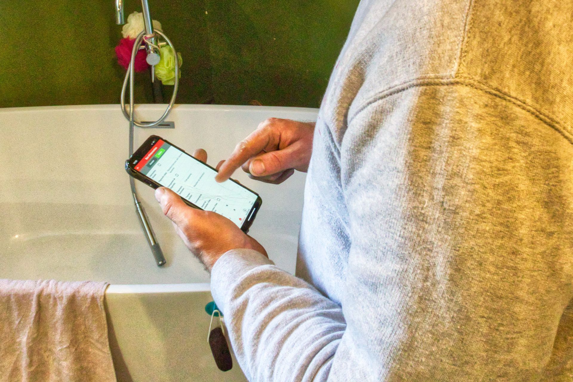 Professionnel qui analyse les travaux sur son téléphone devant une baignoire
