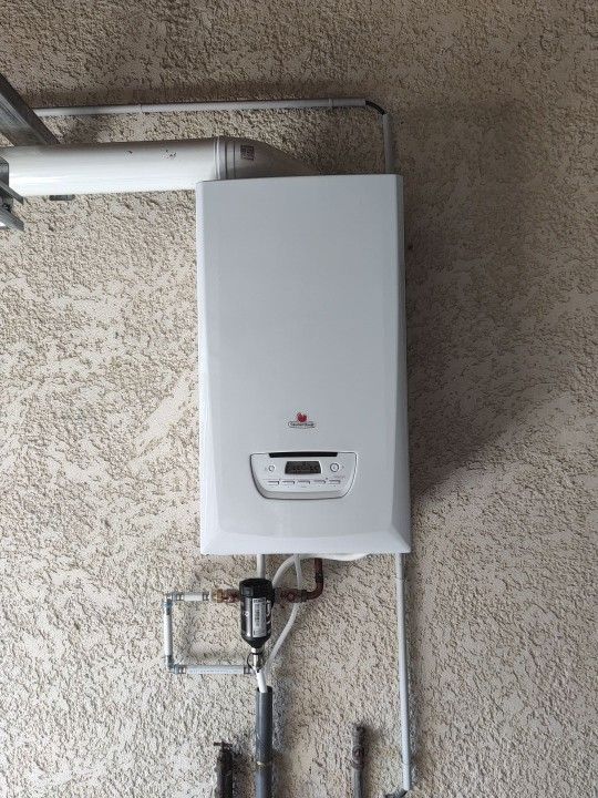 Une chaudière à gaz blanche installée dans un meuble en bois.