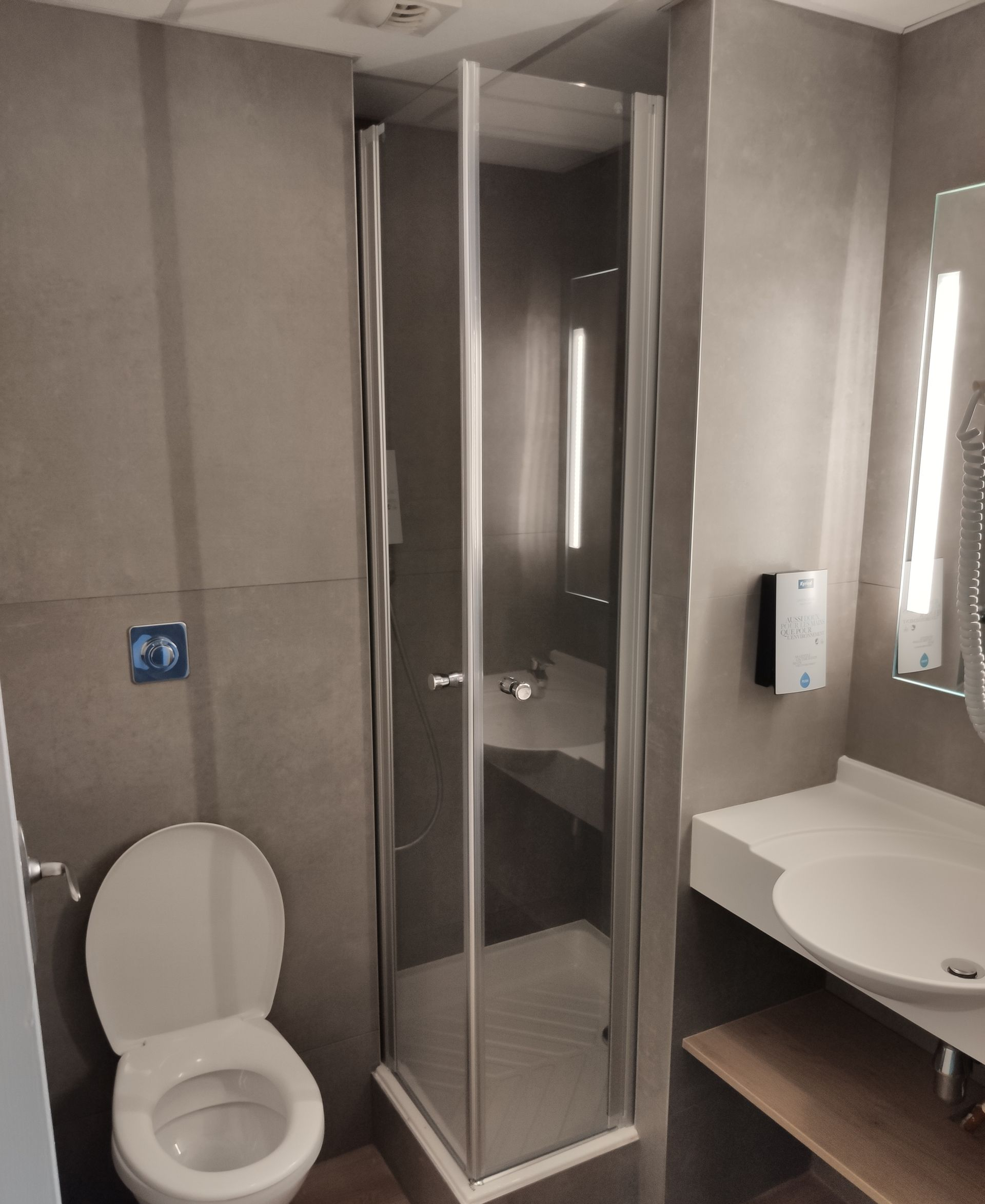 Gros plan sur des éléments de plomberie, notamment pommeau de douche, robinets et tuyaux, en chrome sur fond sombre.