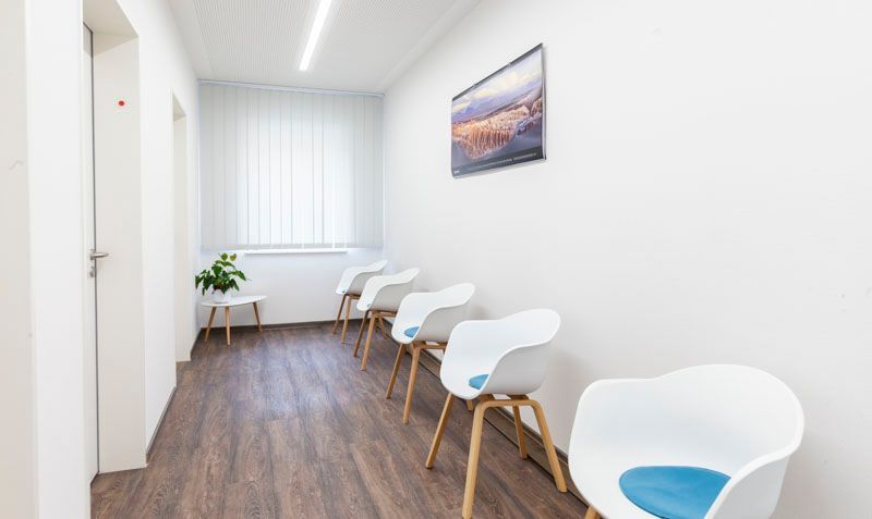 Ein minimalistisches, hell erleuchtetes Wartezimmer in einer Arztpraxis.