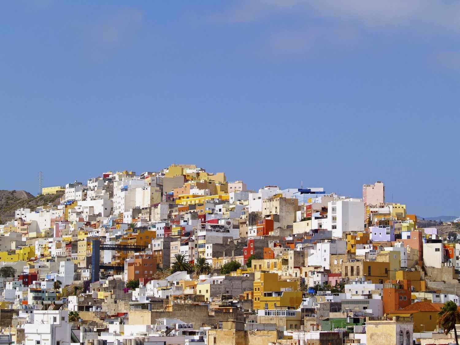 Casas coloridas agrupadas en una ladera bajo un cielo azul claro