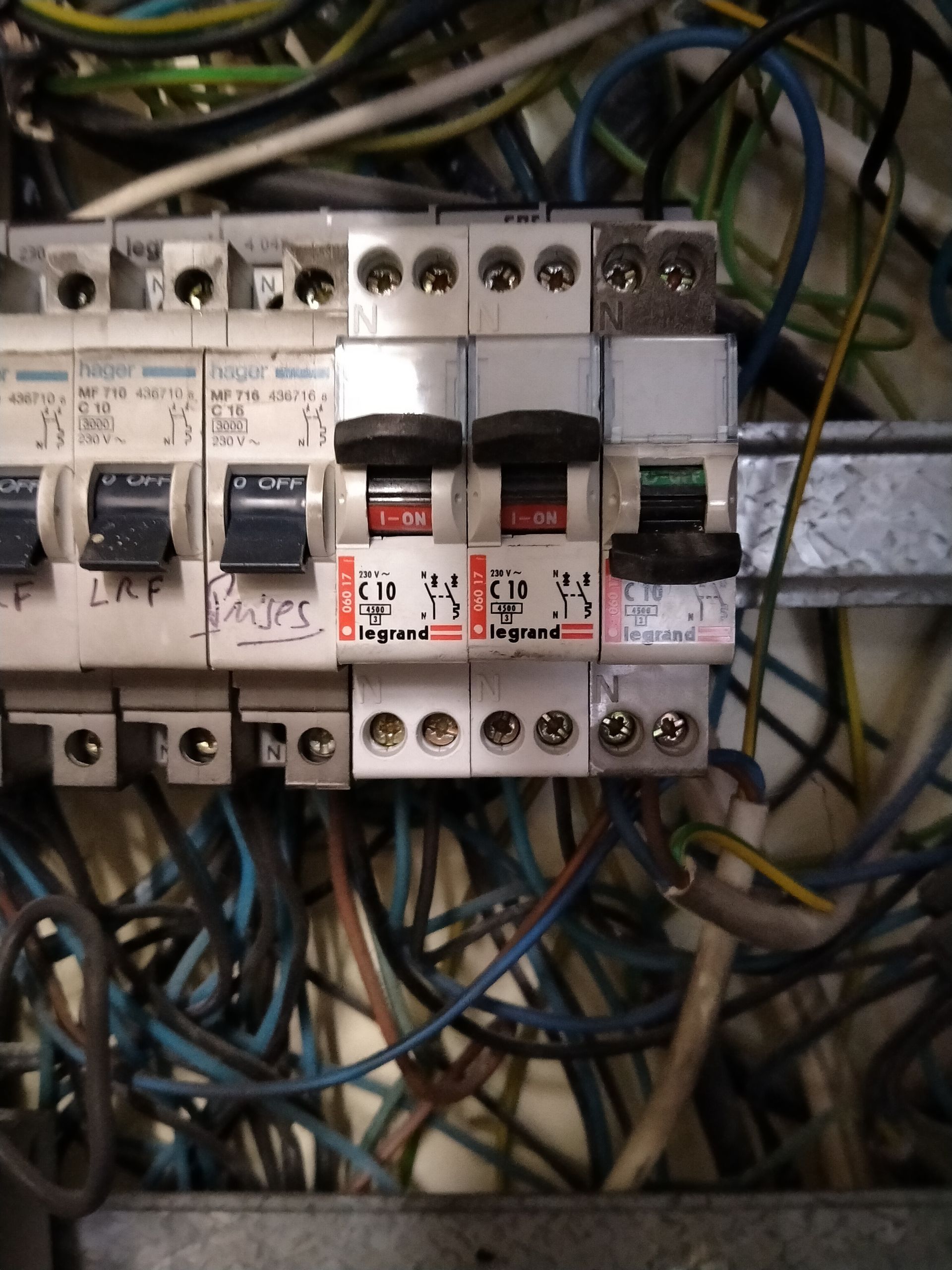 Gros plan sur un tableau de distribution électrique encombré de plusieurs interrupteurs, montrant un interrupteur en position arrêt.