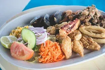 Plato de mariscos con mejillones, calamares fritos y verduras.