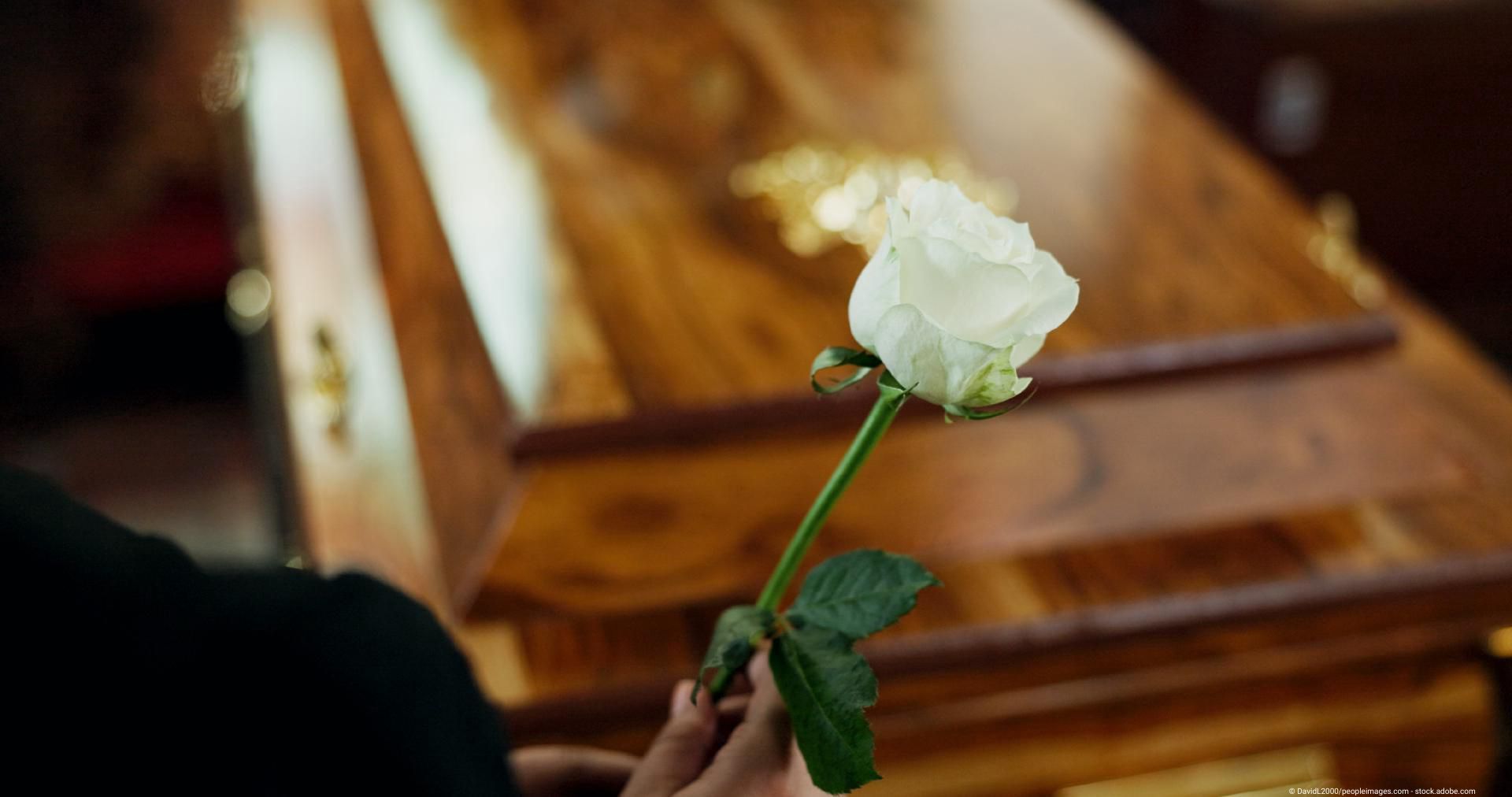 Weiße Rose auf Holzsarg – Symbol für Abschied und Würde