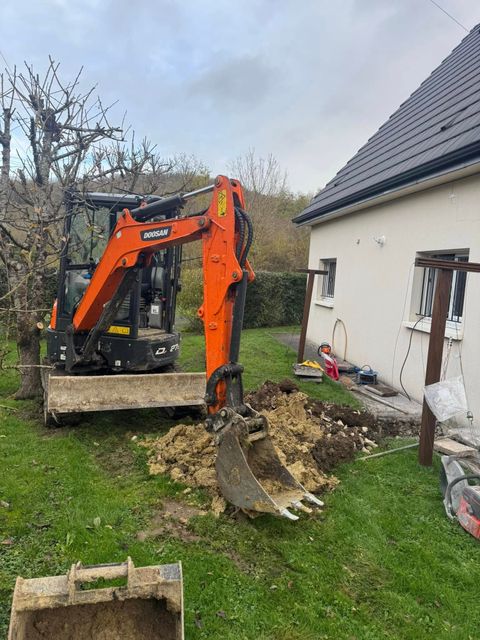 Un engin de chantier à l'arrêt derrière une maison