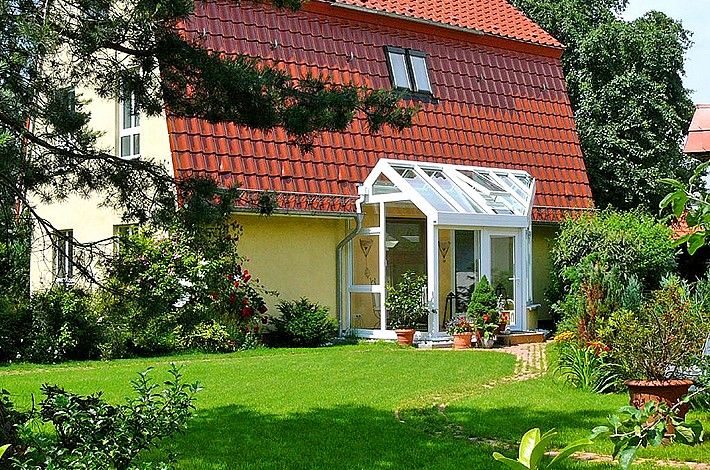 grüne Wiese und Blick auf ein Haus mit rotem Dach