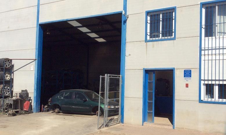 Un coche verde está aparcado delante de un edificio con una gran puerta de garaje.