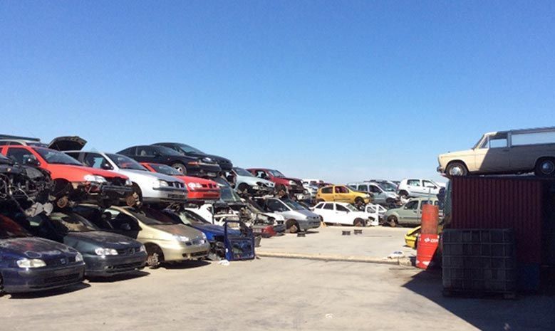 Hay muchos coches apilados uno encima del otro en un estacionamiento.