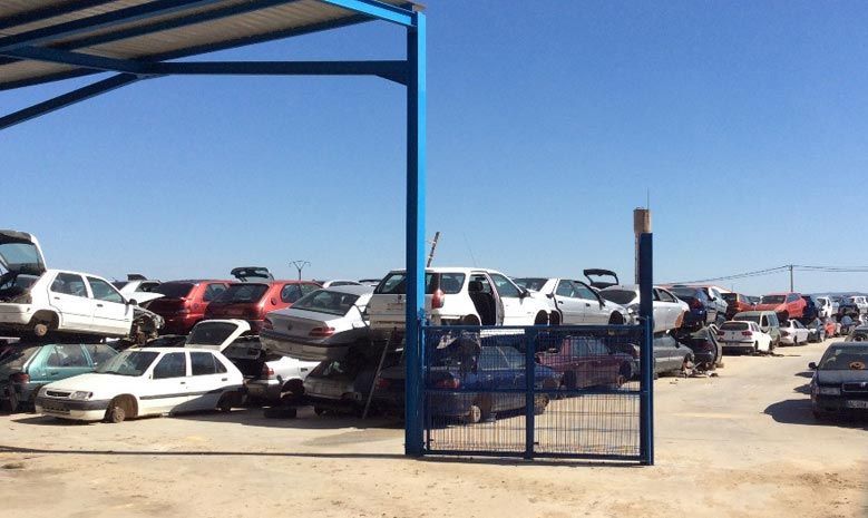 Hay muchos coches apilados uno encima del otro en un estacionamiento.