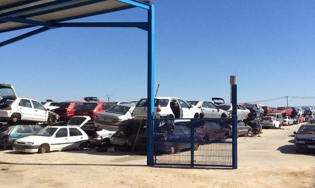 Hay muchos coches apilados uno encima del otro en un estacionamiento.