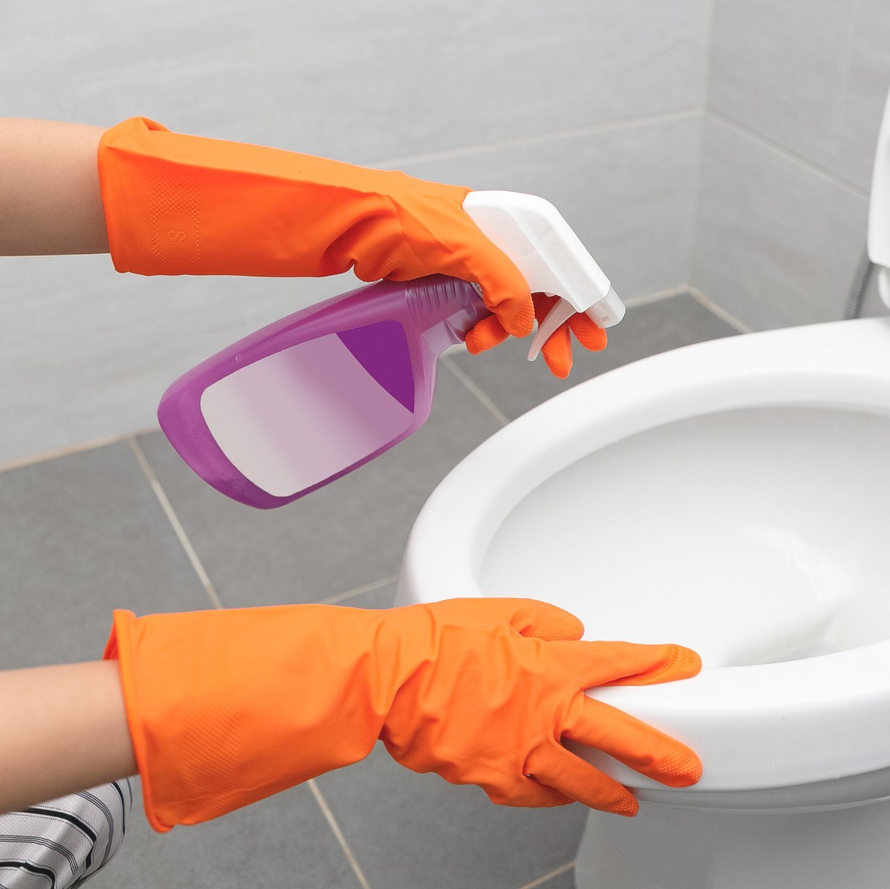 Mains d'un employé de ménage qui nettoie une cuvette de toilette