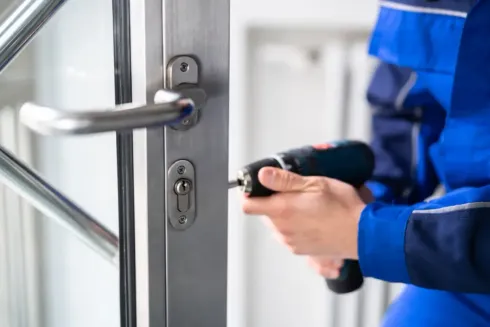Una persona con uniforme azul abre una puerta de cristal con un mando a distancia.
