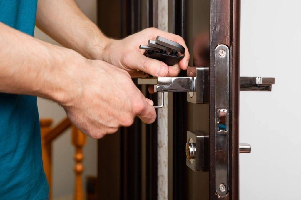 Persona que usa una llave para abrir una puerta de madera oscura con herrajes plateados.