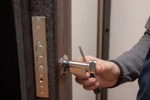 Apertura manual de una puerta con manilla de plata y placa de cerradura de latón.