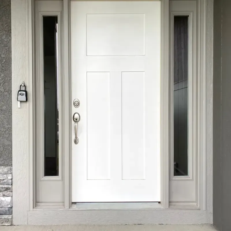 Puerta principal blanca con paneles laterales, caja de seguridad y molduras grises.