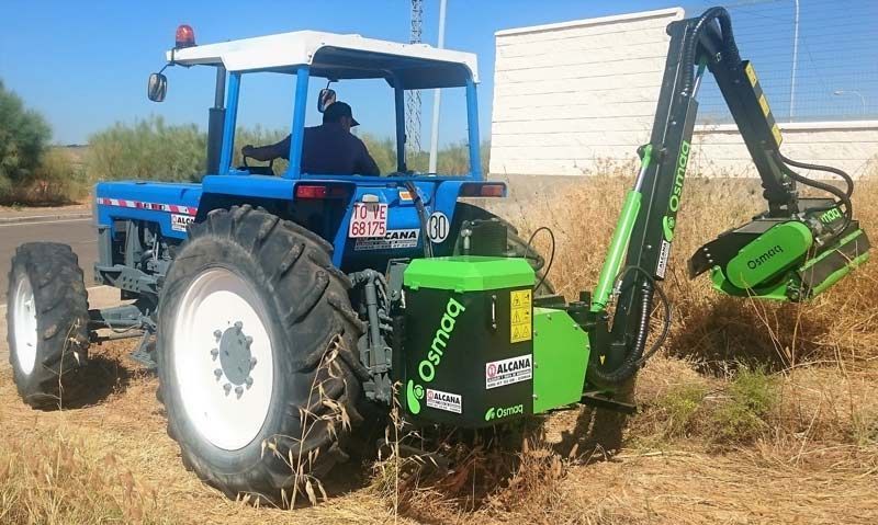 Un tractor azul con una retroexcavadora verde acoplada.