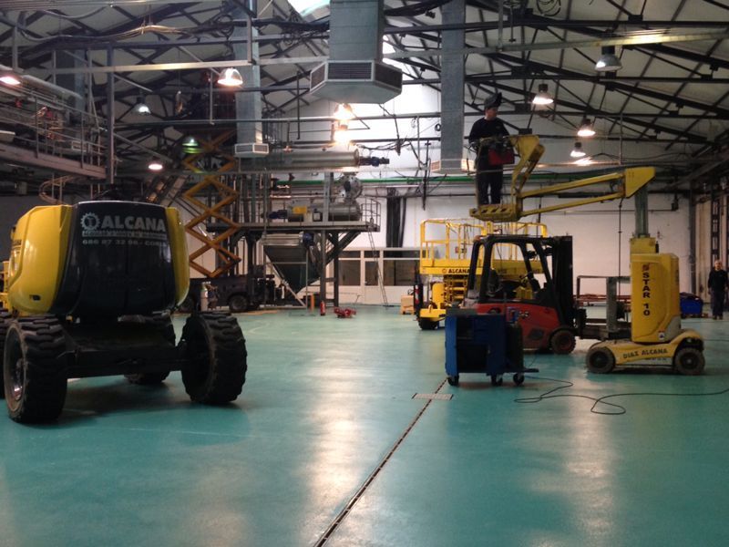 Un hombre está de pie sobre una carretilla elevadora en un gran almacén.