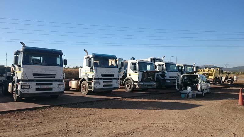 Una fila de camiones están estacionados en un lote de tierra