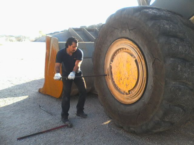 Un hombre está parado junto a un gran neumático amarillo.