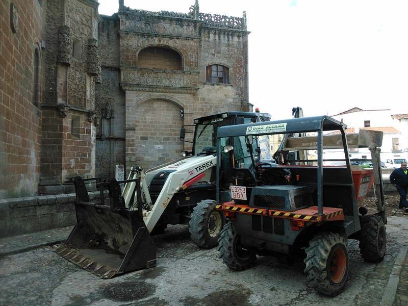 Dos tractores están estacionados frente a un edificio de ladrillos.