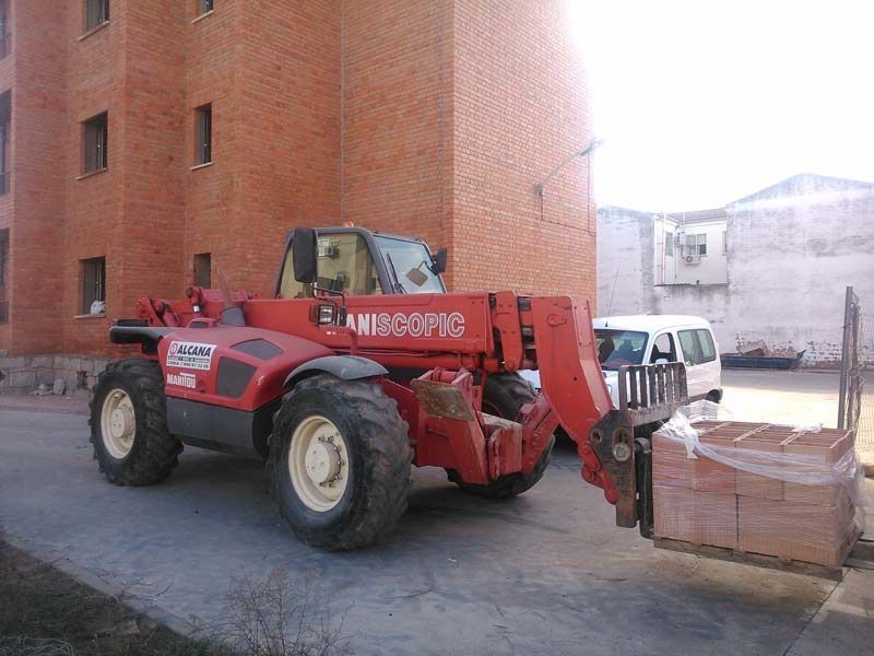 Una carretilla elevadora roja está estacionada frente a un edificio de ladrillos.