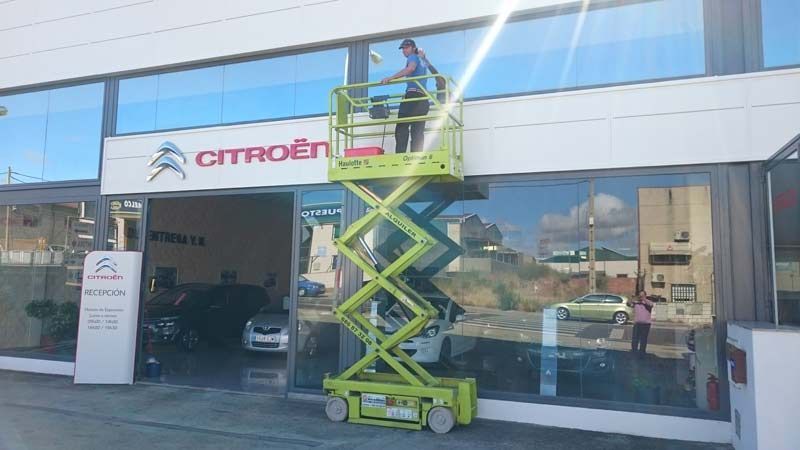 Un hombre está limpiando las ventanas de un concesionario de automóviles Citroën.