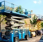 Un elevador de tijera azul está estacionado al costado de la carretera.