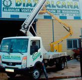 Un camión blanco con una grúa encima está estacionado frente a un edificio.