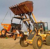 Una excavadora con un cucharón grande está estacionada al lado de un camión volquete.