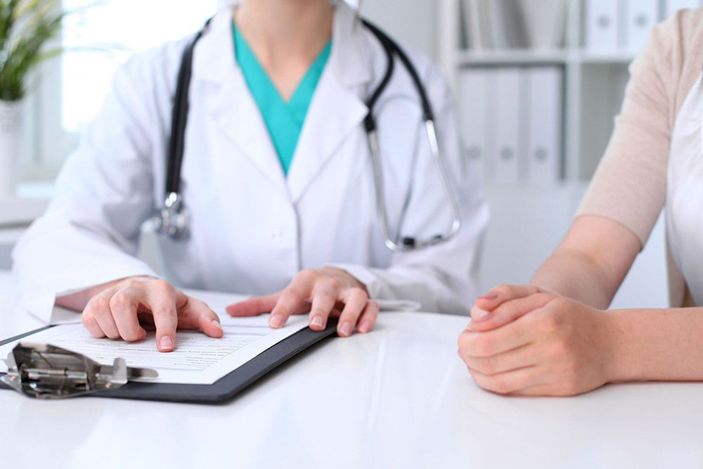 El médico y el paciente hablan de unos documentos en el mostrador de la clínica
