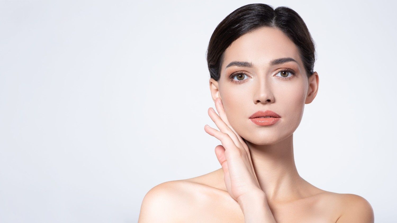 Una persona de cabello oscuro mira a la cámara con expresión neutra, apoyando la mano en la mejilla.
