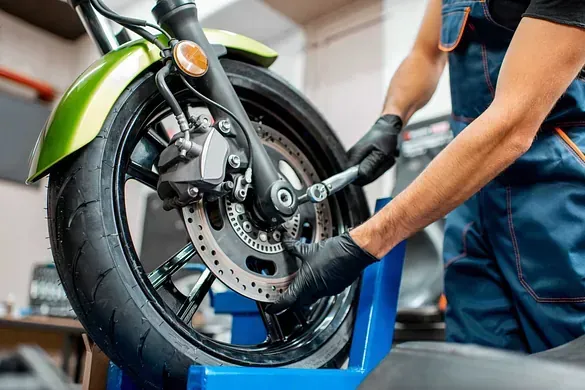 Un hombre está trabajando en una rueda de motocicleta en un garaje.