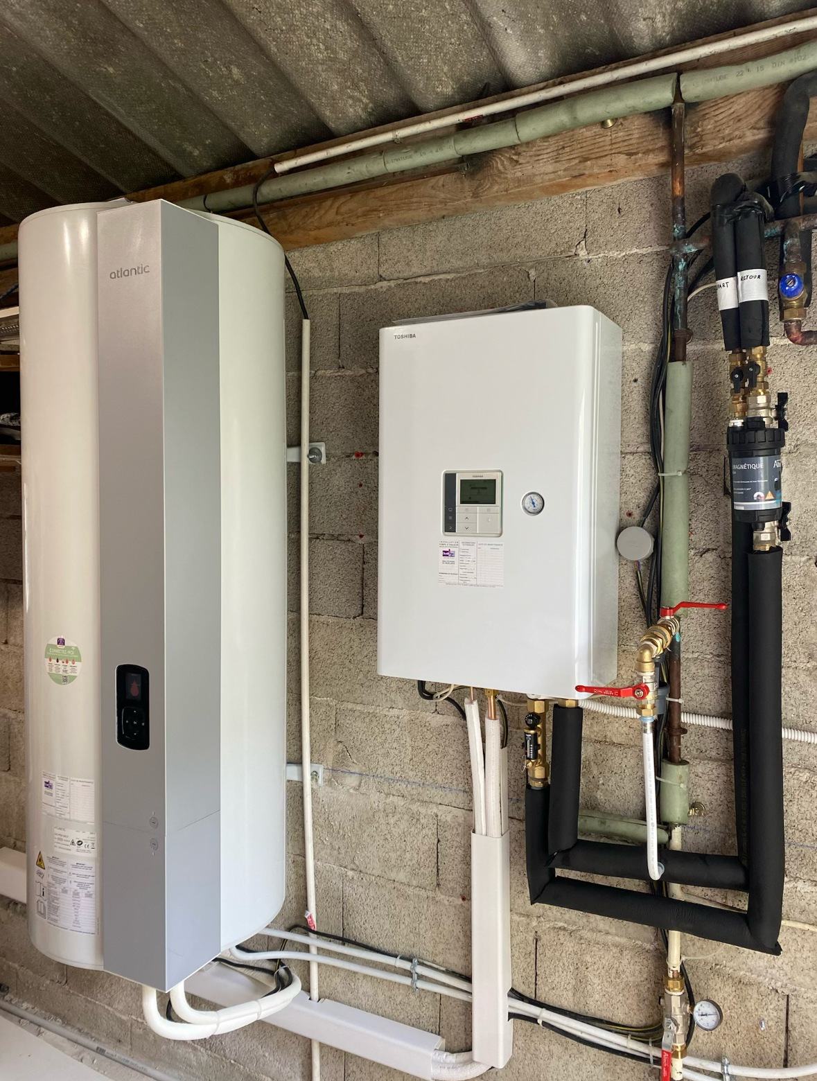 Chauffe-eau blanc de grande taille, fixé sur un mur carrelé dans une cuisine.