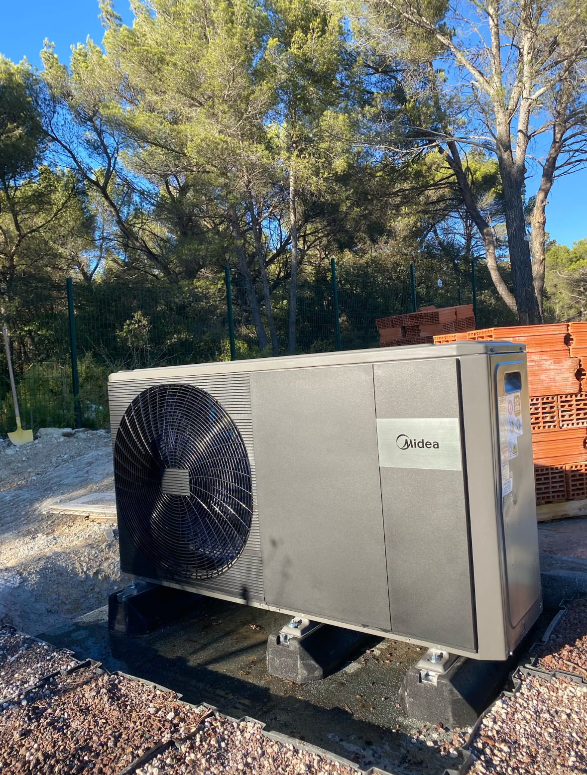 Appareils blancs de chauffage, avec affichage électronique et tuyauterie, installés sur un mur en béton.