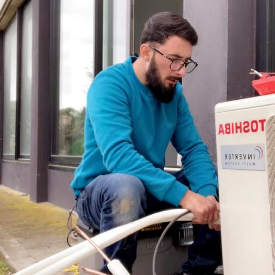 Loïc de LD-Energies installe un climatiseur à l'extérieur d'un bâtiment.