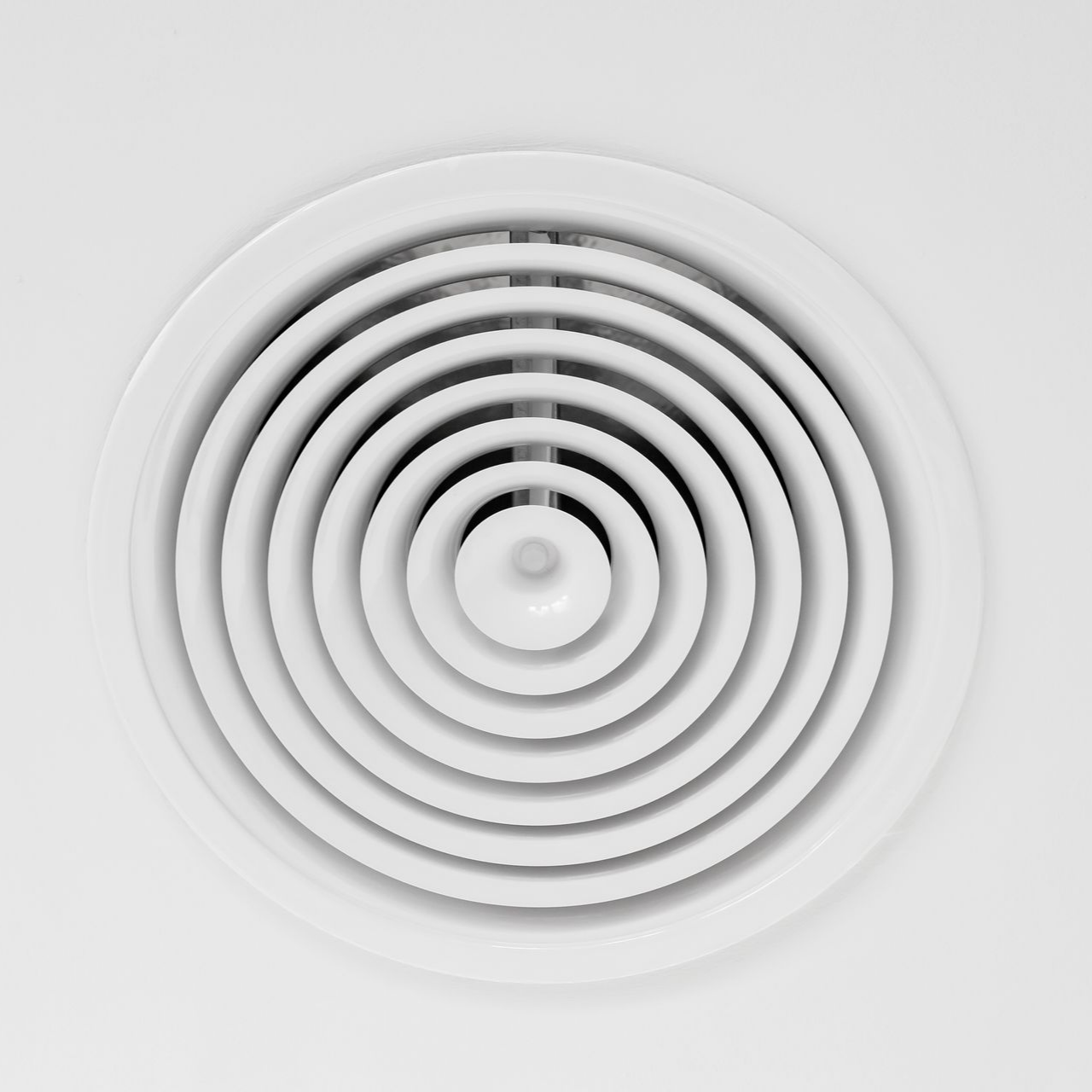 Grille d'aération circulaire blanche au plafond.
