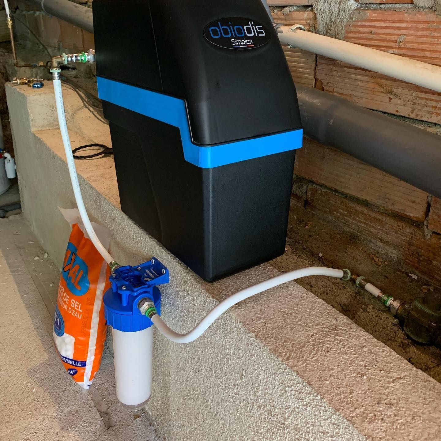 Adoucisseur et système de filtration d'eau installés dans un sous-sol, avec un sac de sel.