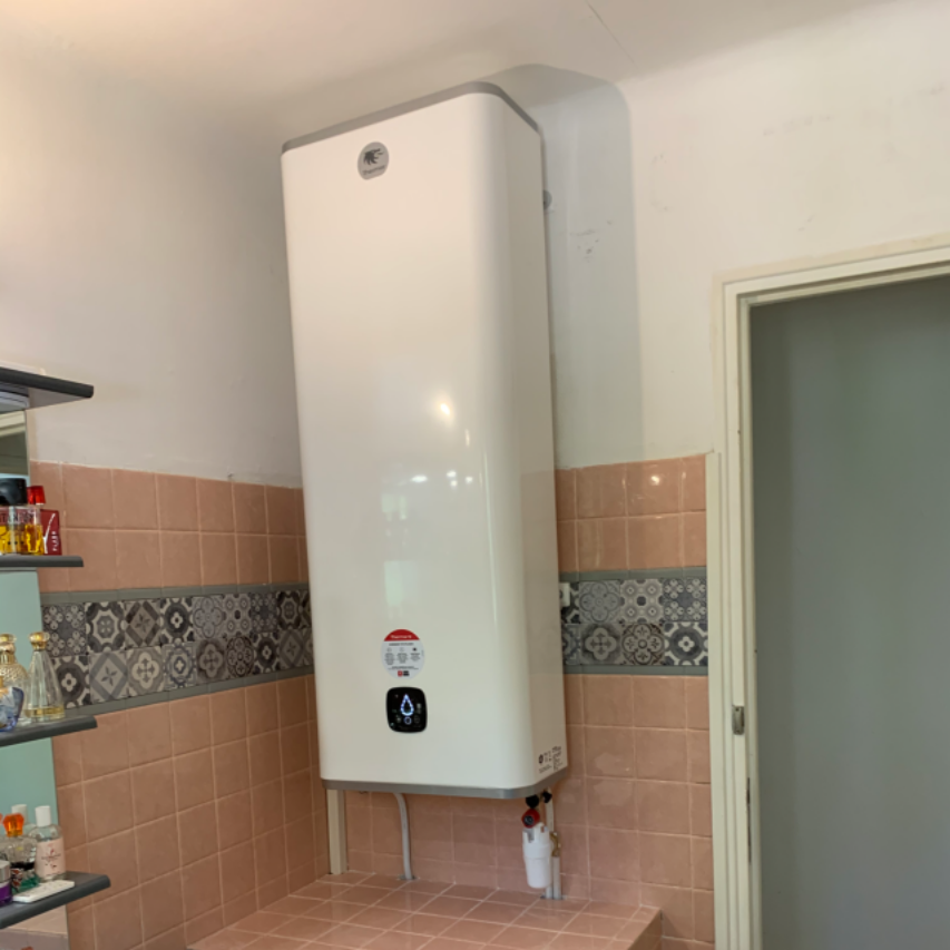 Chauffe-eau blanc de grande taille, fixé sur un mur carrelé dans une cuisine.