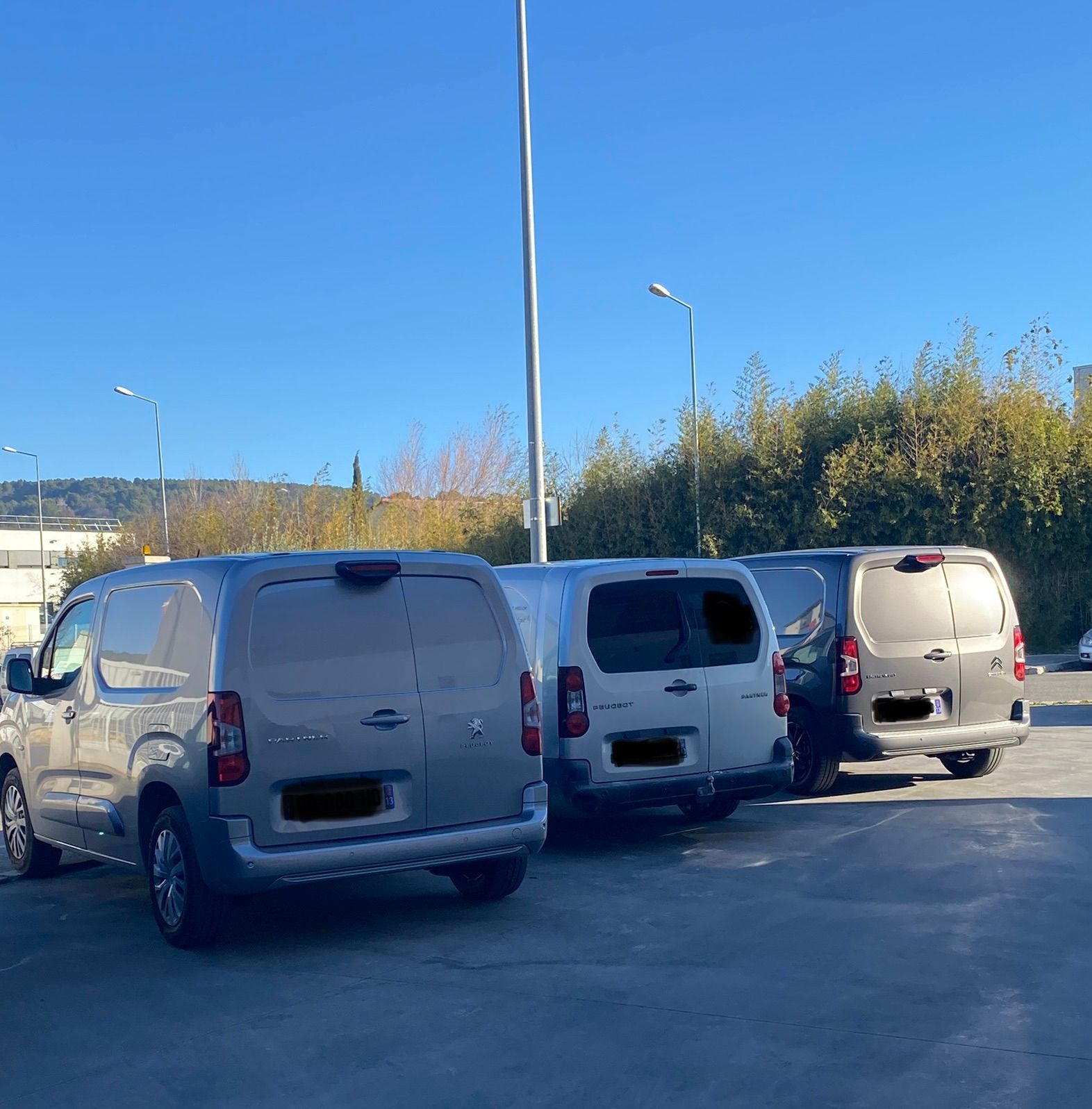 Deux camionnettes LD-Energies garées sur un chemin de terre, des arbres en arrière-plan, ciel bleu.