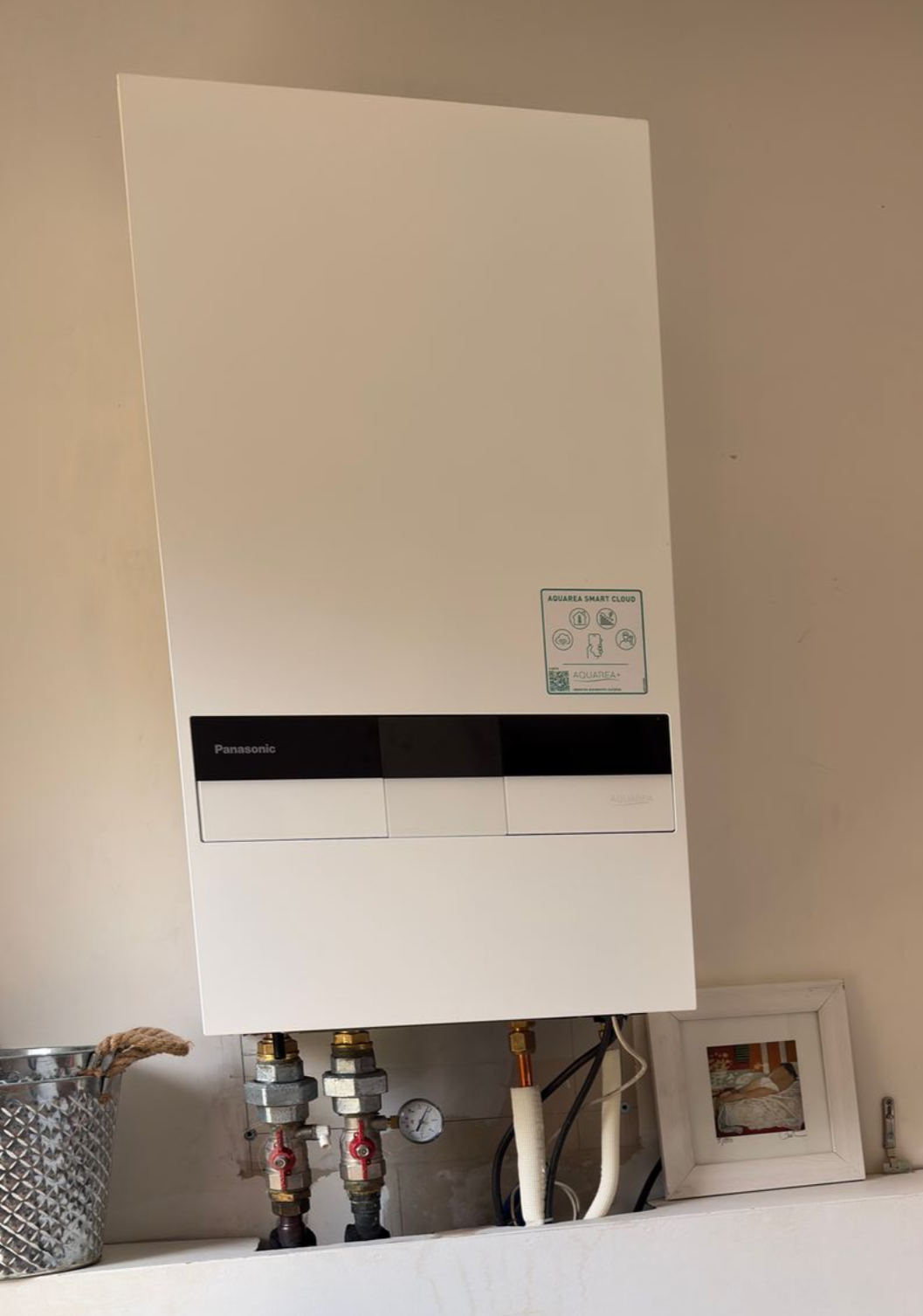 Pompe à chaleur air-air Midea sur socle en béton, couleur beige, avec tuyaux de protection, installation extérieure.