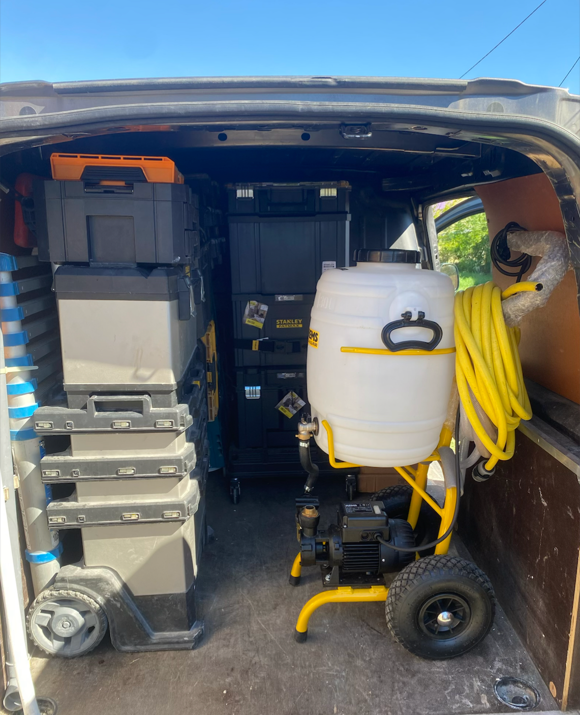 Intérieur d'une fourgonnette remplie de boîtes à outils noires et grises empilées.