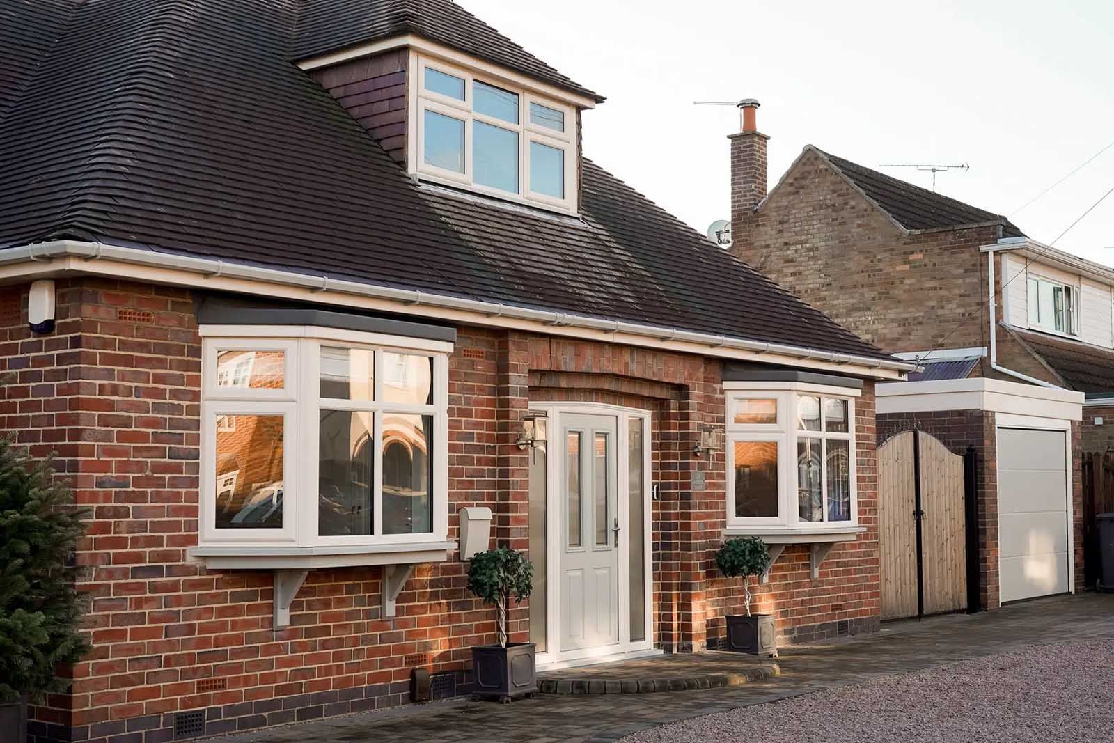 A brick house with white windows and a garage in front of it.
