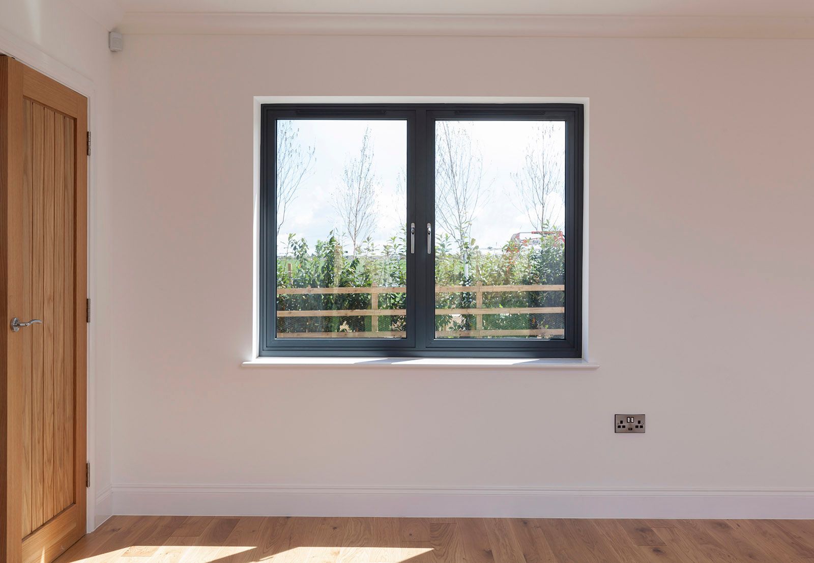 An empty room with a window and a wooden floor.