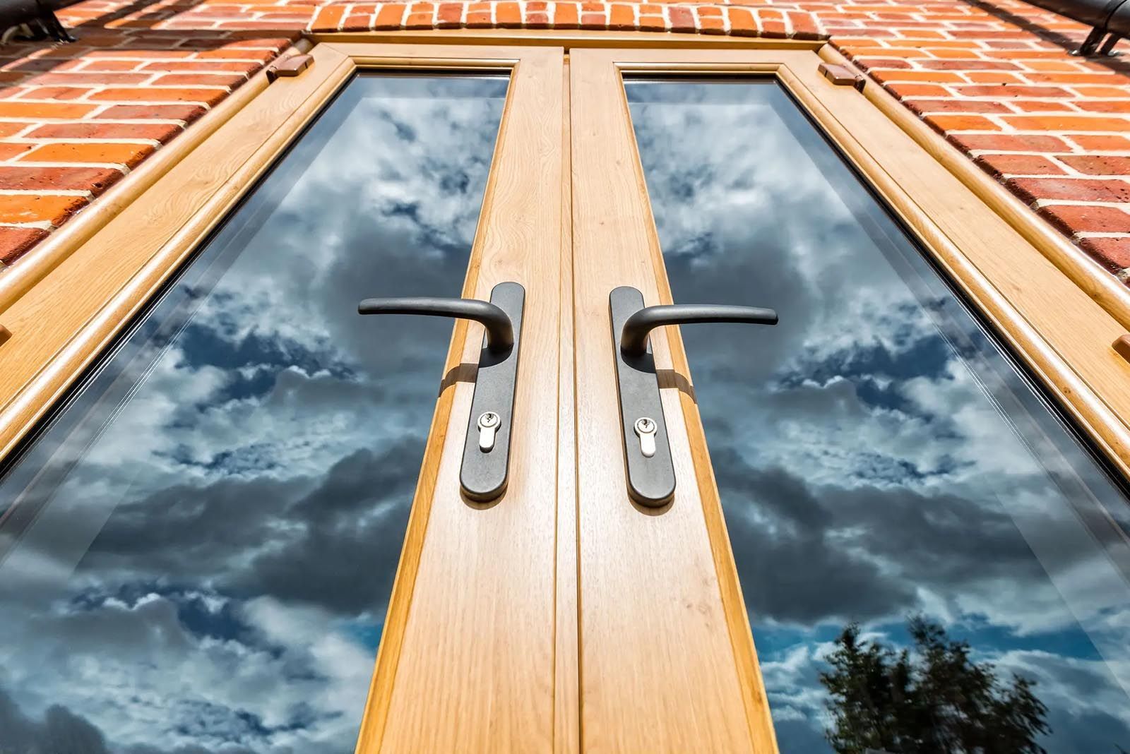 A close up of a door with a cloudy sky reflected in the glass.