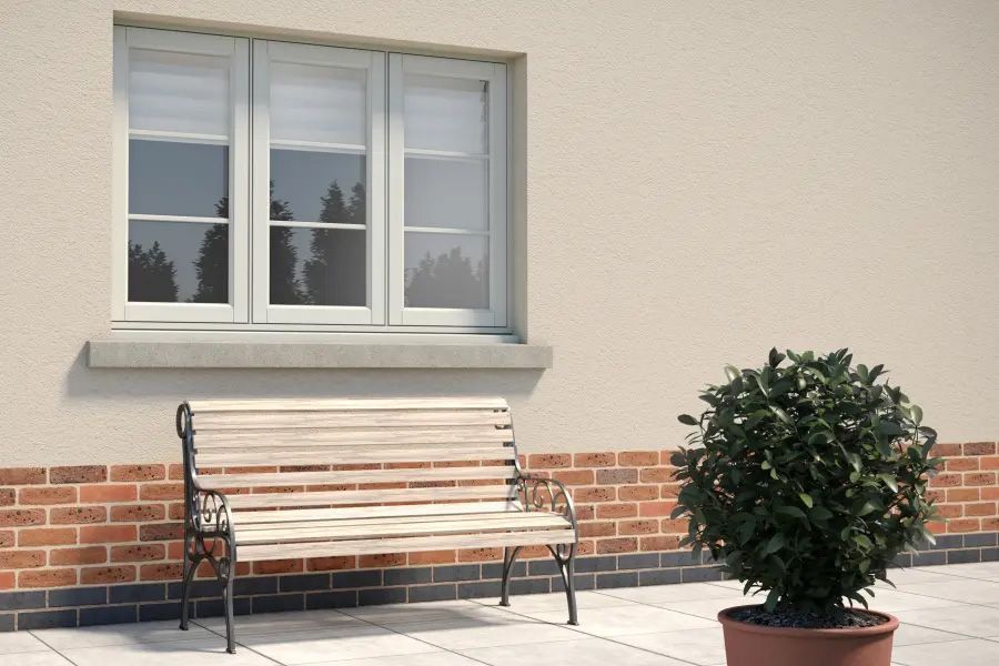 A wooden bench is sitting in front of a window next to a potted plant.