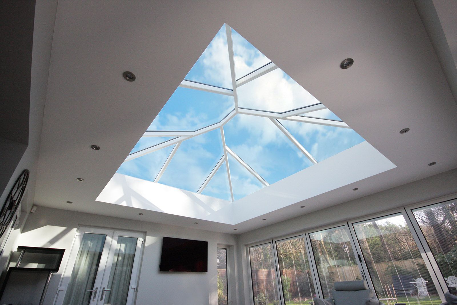 A living room with a pyramid shaped skylight in the ceiling.