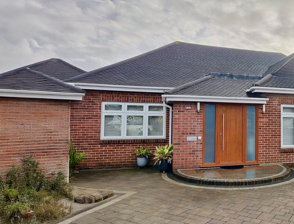 A brick house with a black roof and a wooden door